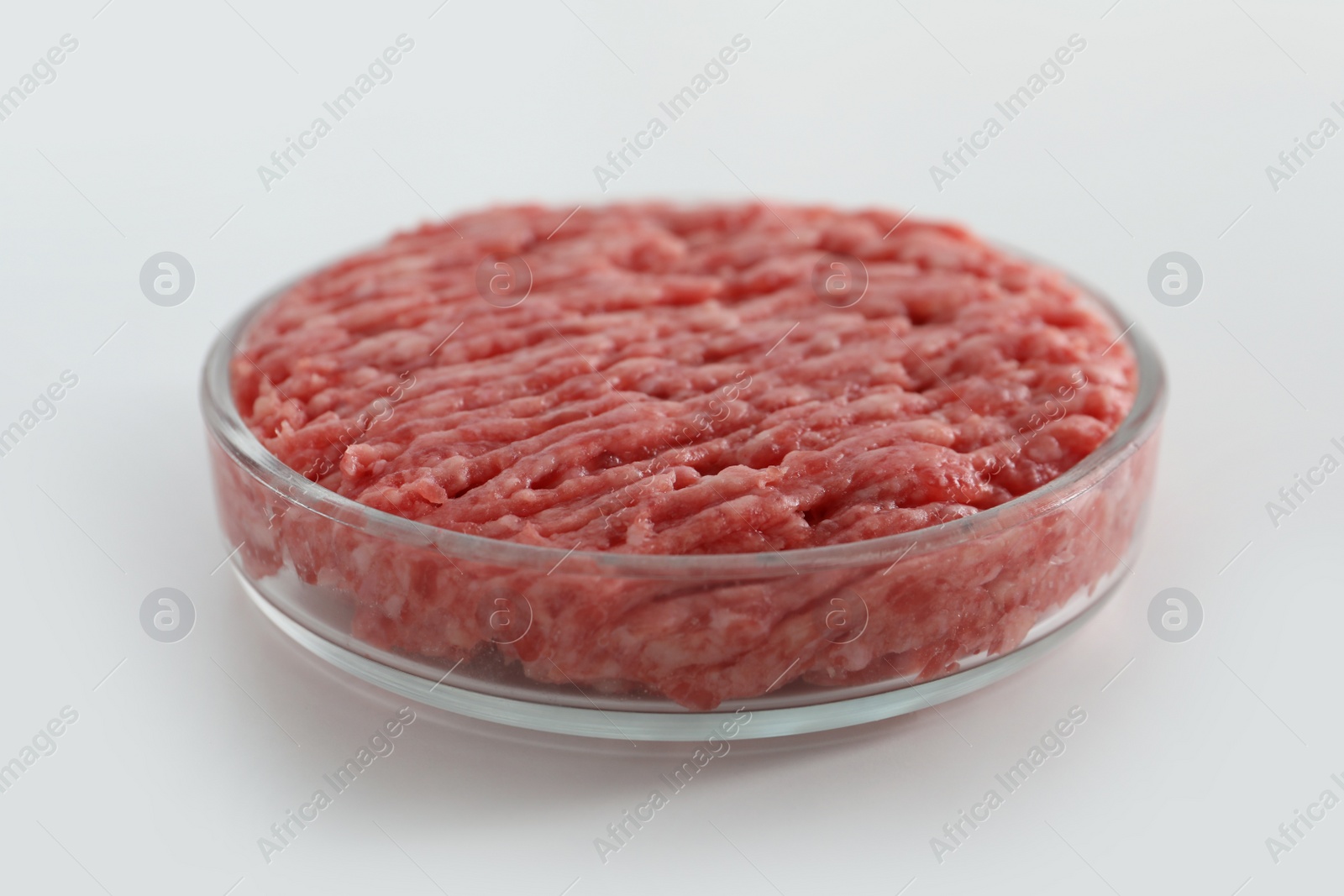 Photo of Petri dish with raw minced cultured meat on white table, closeup