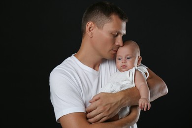 Photo of Happy father with his little baby on black background