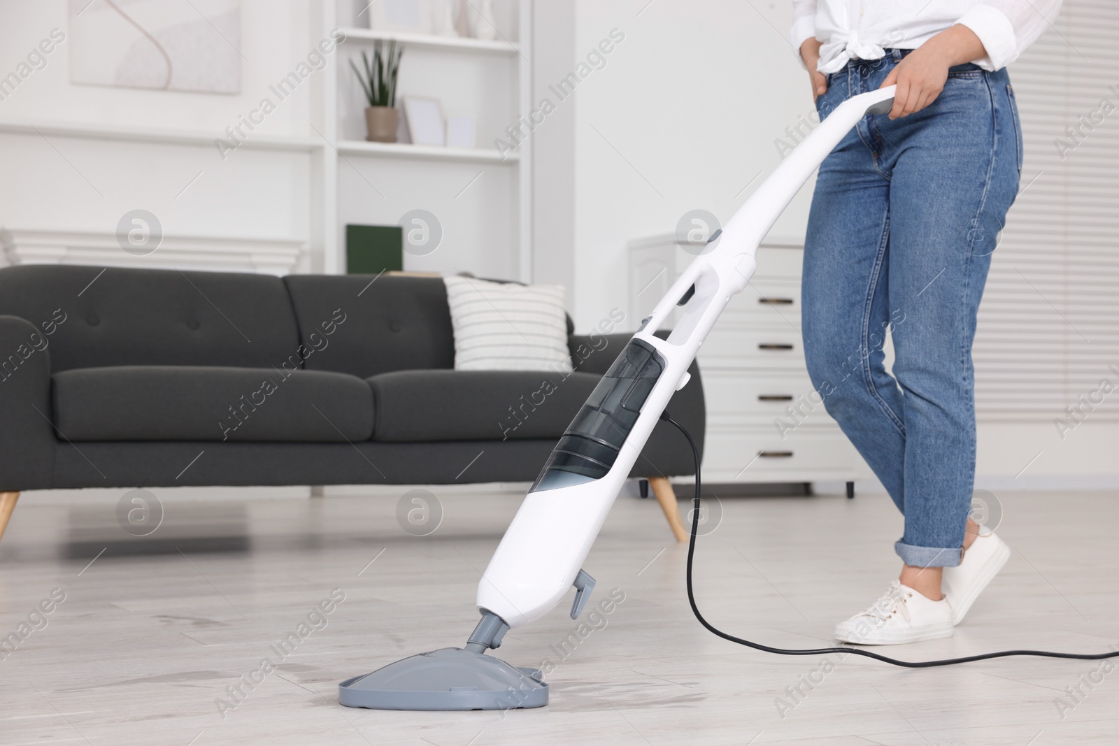 Photo of Woman cleaning floor with steam mop at home, closeup