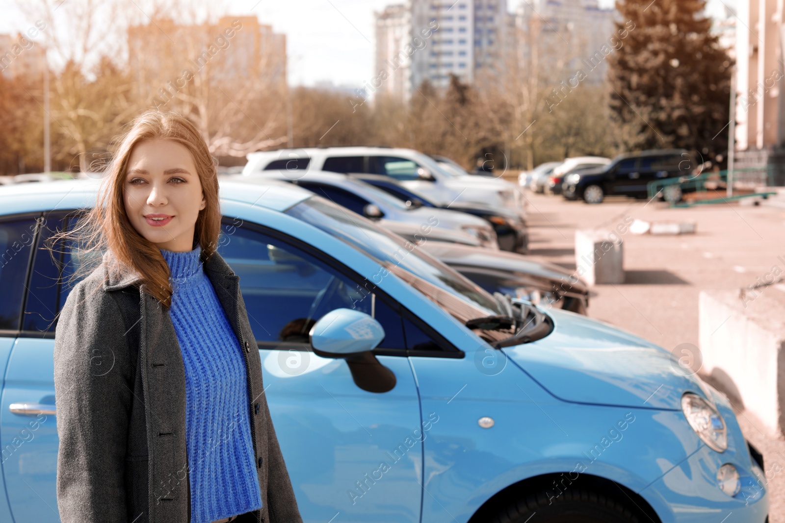 Photo of Portrait of beautiful young woman near parked cars on sunny day