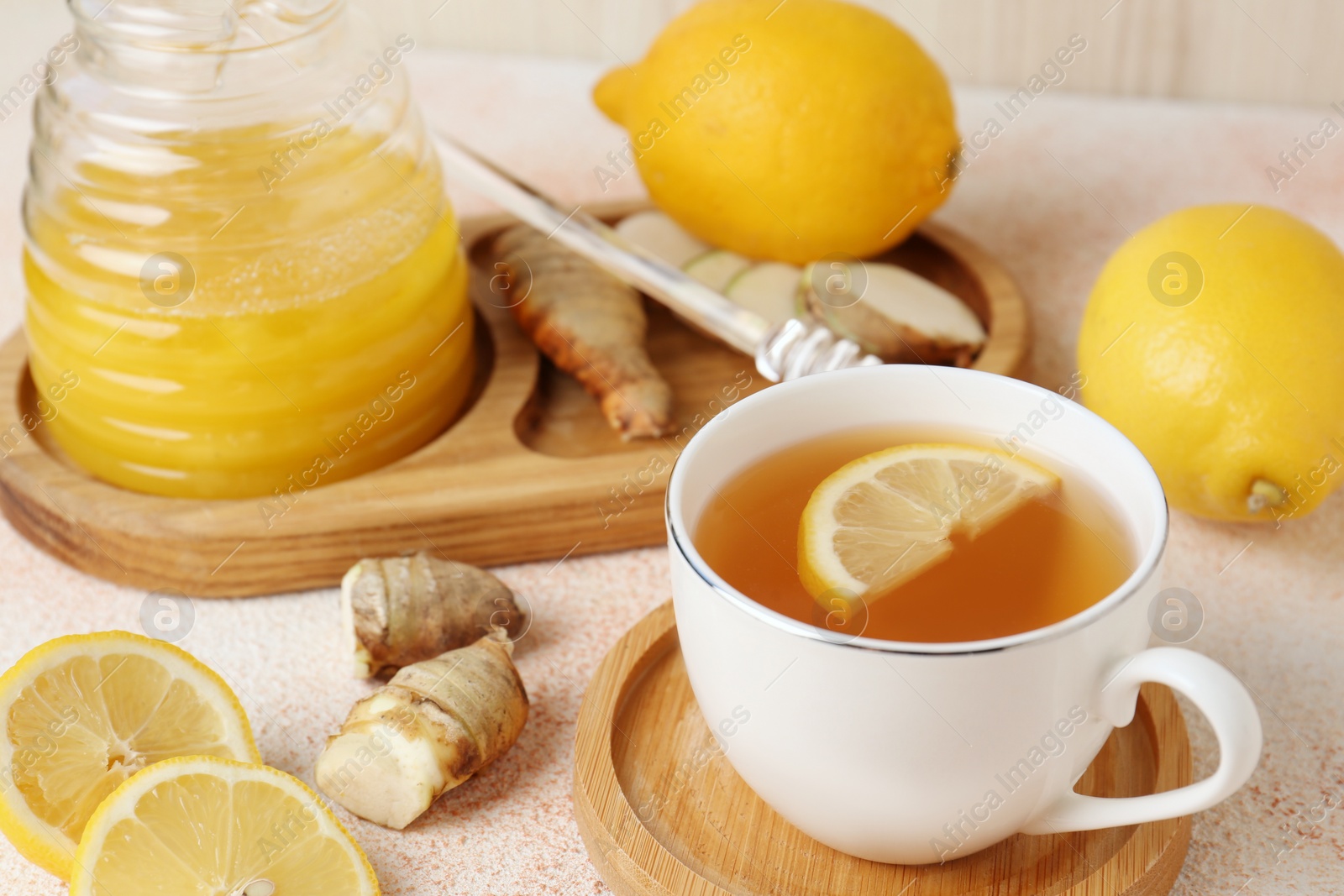 Photo of Tea, honey, lemon and ginger on beige textured table