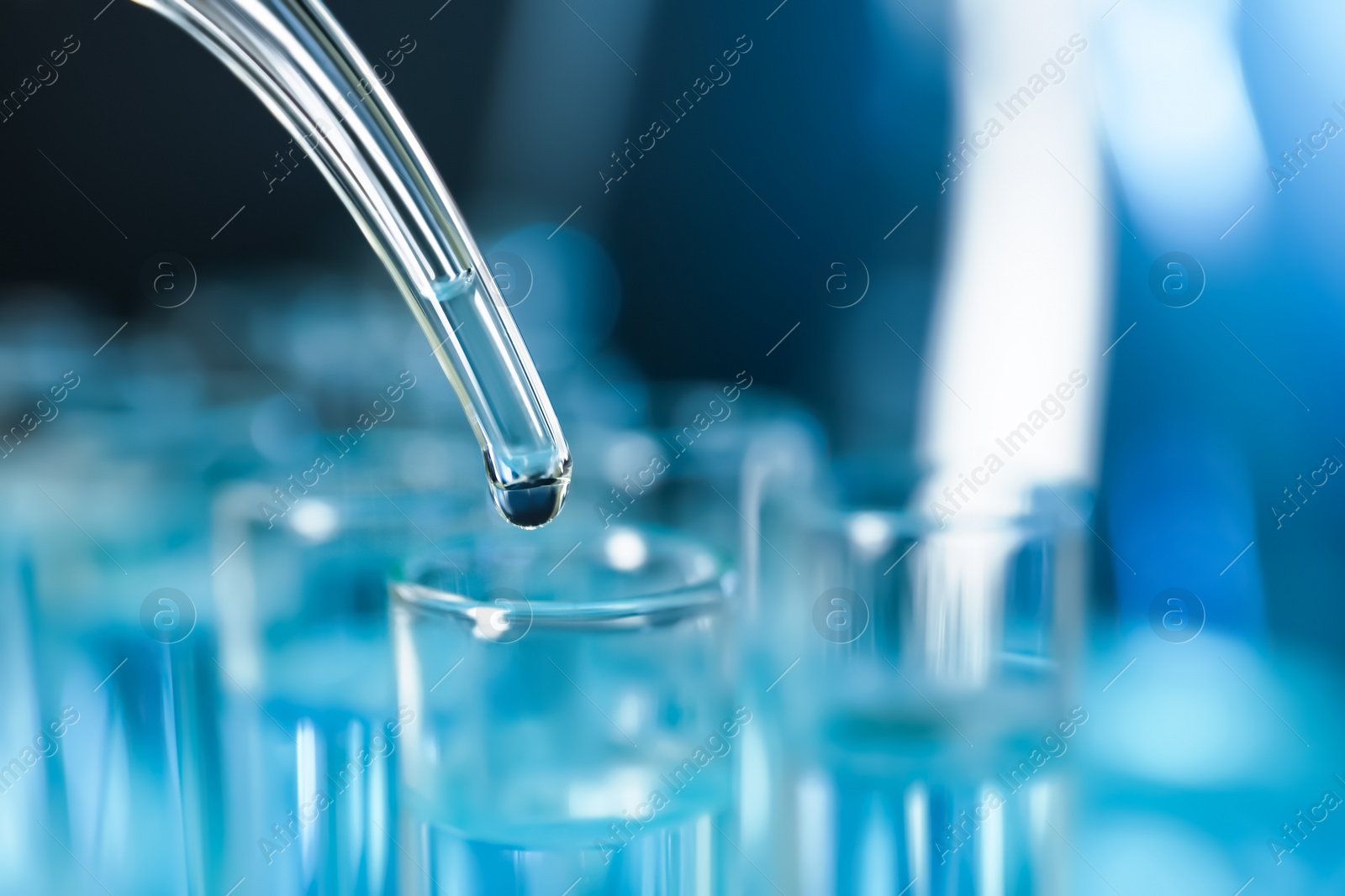 Photo of Dripping liquid into test tube, closeup with space for text. Solution chemistry