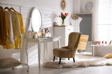 Stylish room interior with elegant dressing table, mirror and comfortable chair