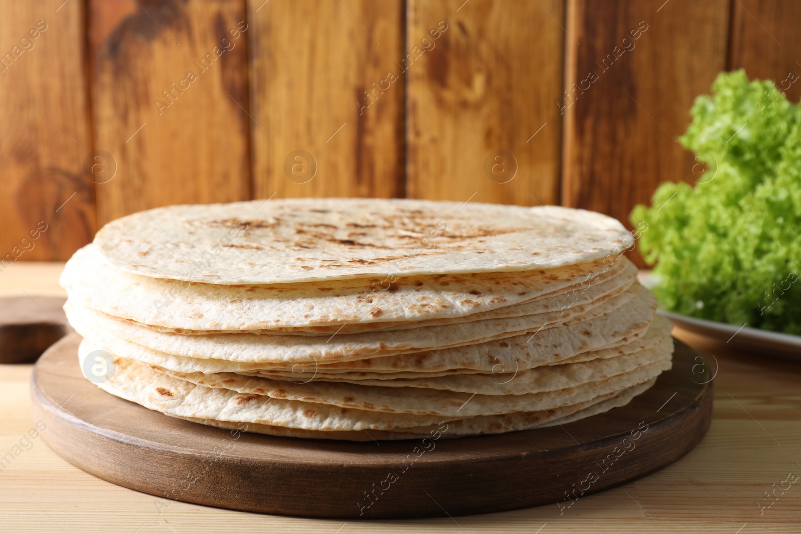 Photo of Many tasty homemade tortillas on wooden table