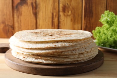 Many tasty homemade tortillas on wooden table