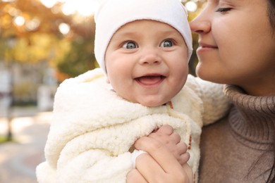 Photo of Happy mother with her baby daughter outdoors on autumn day, closeup