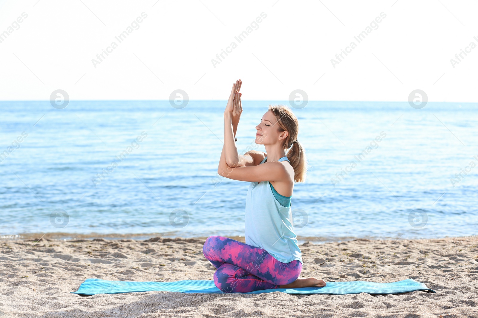 Photo of Young woman doing yoga exercises on beach in morning