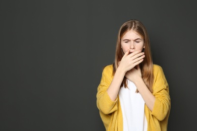 Photo of Teenage girl suffering from cough on dark background. Space for text