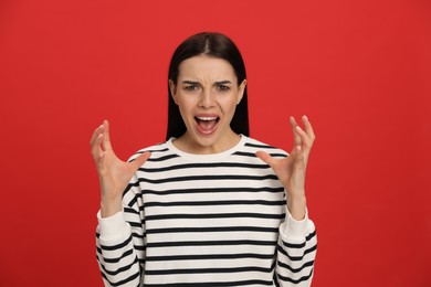 Photo of Angry young woman on red background. Hate concept