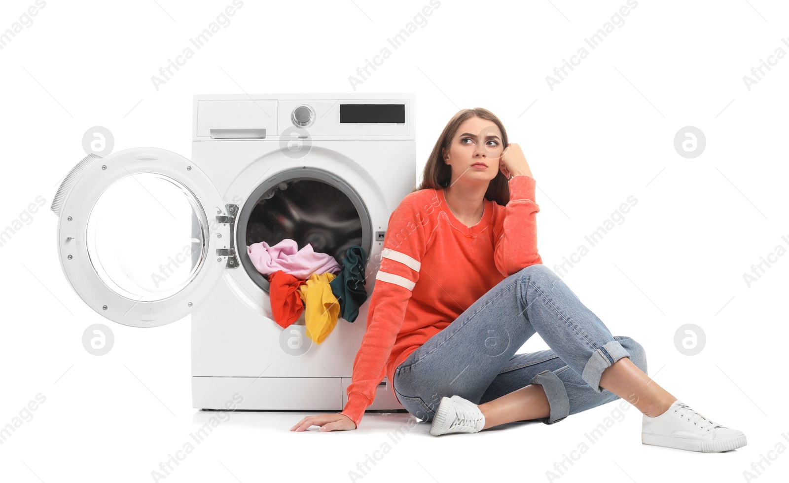 Photo of Young woman sitting near washing machine with dirty laundry on white background