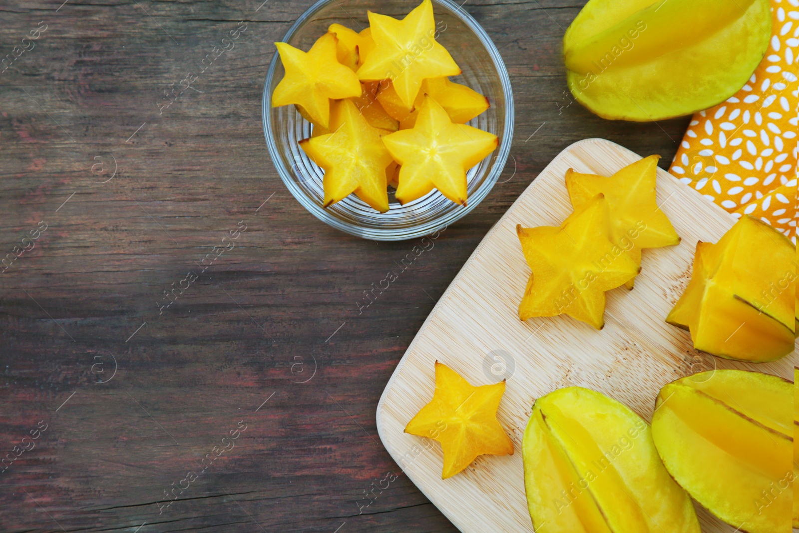 Photo of Delicious cut and whole carambolas on wooden table, flat lay. Space for text