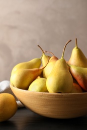 Photo of Bowl with ripe pears on table against grey background. Space for text