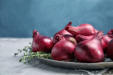 Photo of Plate with ripe red onions on table