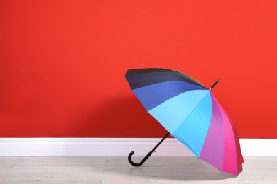 Photo of Beautiful colorful umbrella near red wall. Space for text