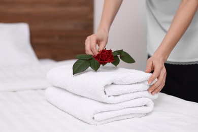 Photo of Chambermaid putting flower on fresh towels in hotel room, closeup