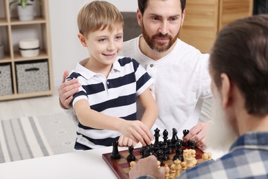 Family playing chess together at table in room