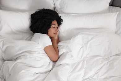 Beautiful young woman sleeping in soft bed, top view