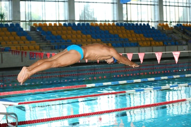 Photo of Young athletic man jumping into swimming pool