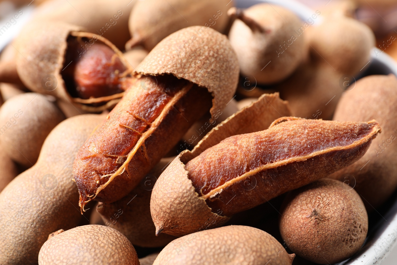 Photo of Many delicious ripe tamarinds in bowl, closeup