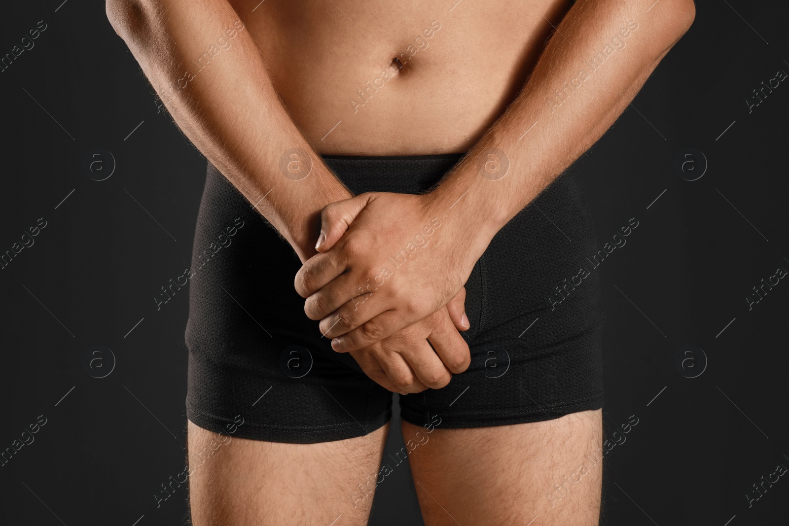 Photo of Man suffering from pain on black background, closeup. Urology problems