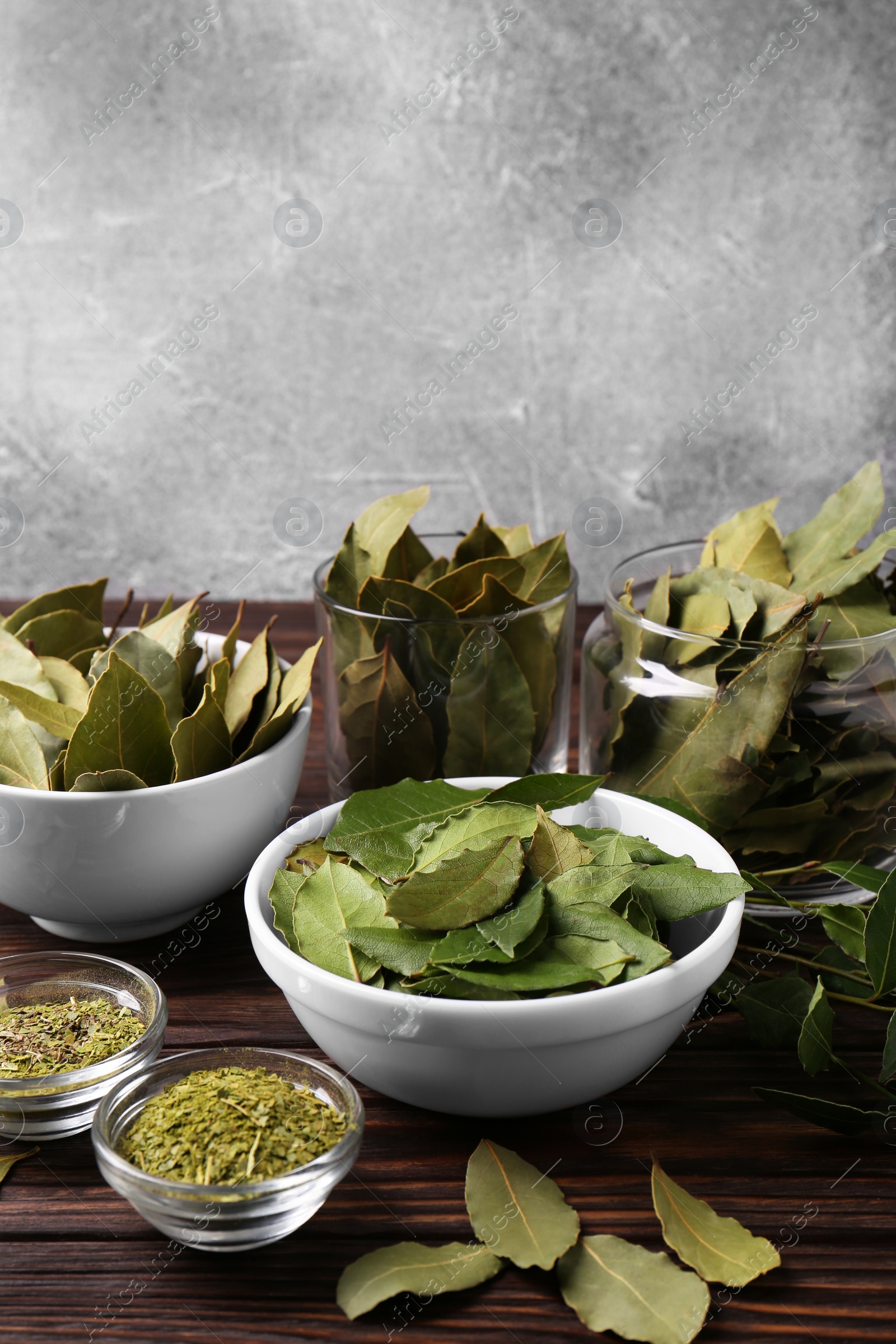 Photo of Bowls with ground, fresh and dry bay leaves on wooden table