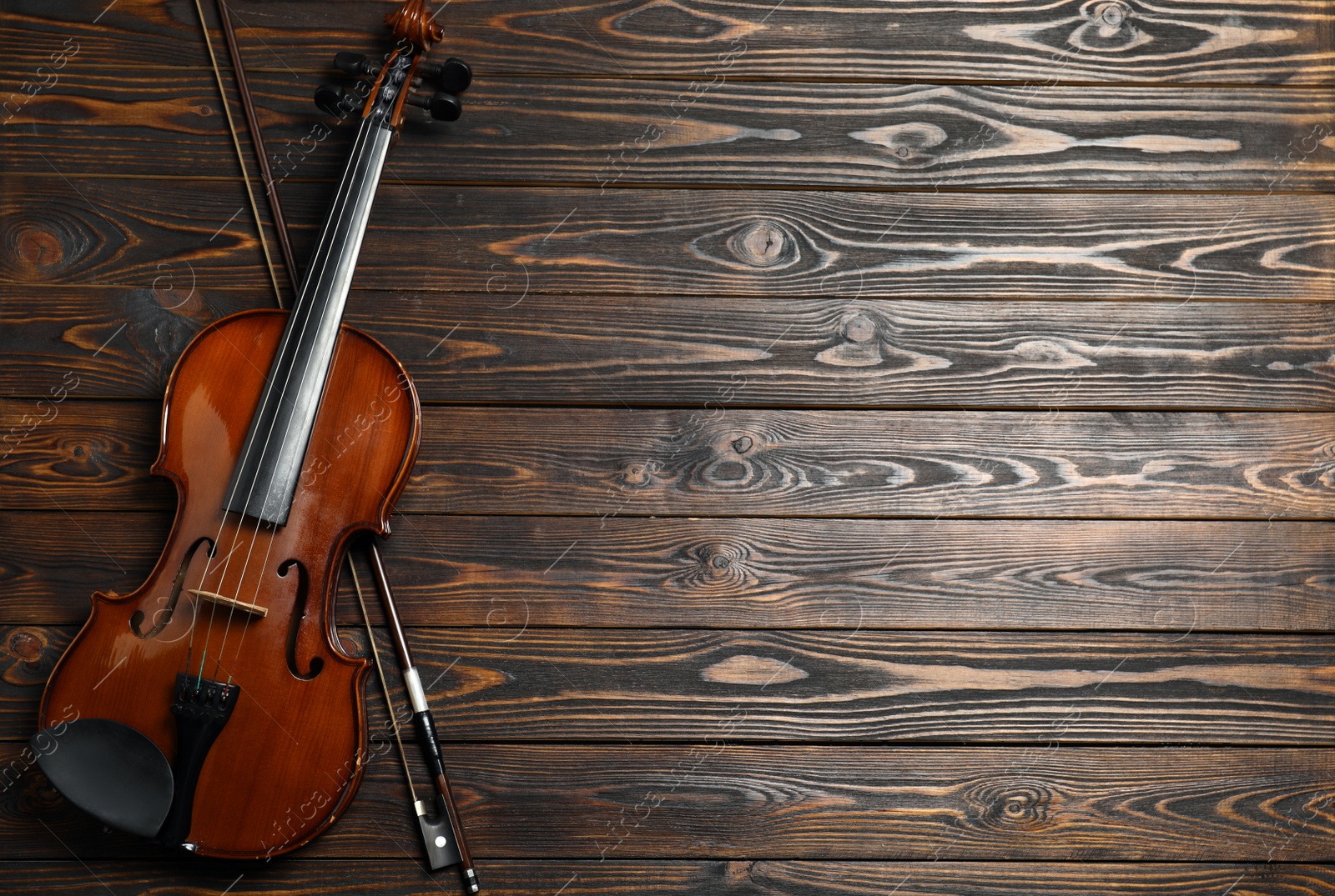 Photo of Classic violin and bow on wooden background, top view. Space for text