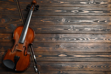 Photo of Classic violin and bow on wooden background, top view. Space for text