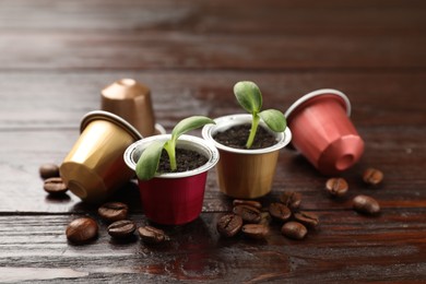 Photo of Coffee capsules, seedlings and beans on wooden table, closeup