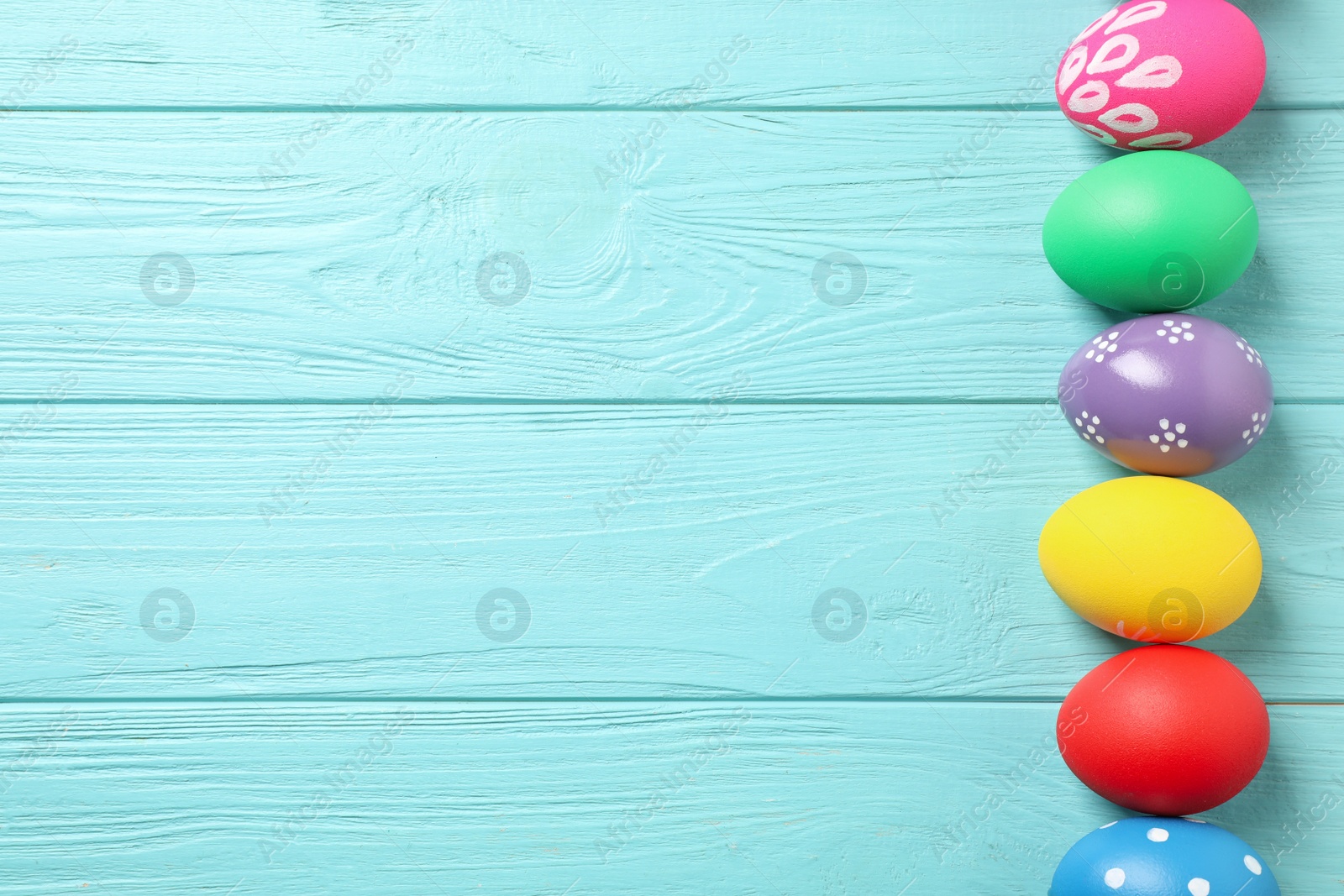 Photo of Colorful Easter eggs on light blue wooden background, flat lay. Space for text