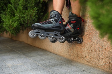 Photo of Young man with roller skates outdoors, closeup