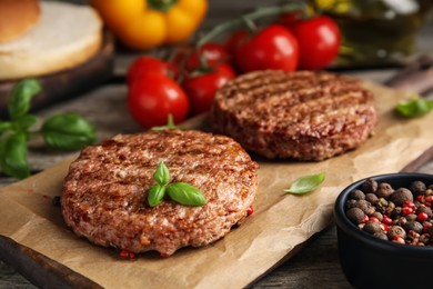 Photo of Tasty grilled hamburger patties with basil served on table, closeup