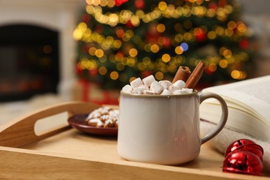 Christmas cocoa with marshmallows and cinnamon sticks in grey cup on wooden tray indoors, closeup. Space for text