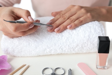 Photo of Woman preparing fingernail cuticles at table, closeup. At-home manicure