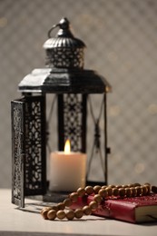 Photo of Arabic lantern, Quran and misbaha on white table