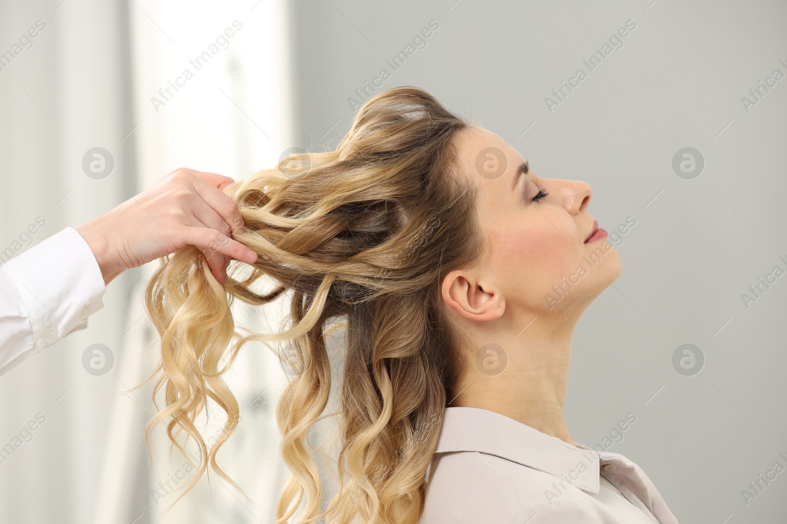 Photo of Hair styling. Professional hairdresser working with client indoors, closeup