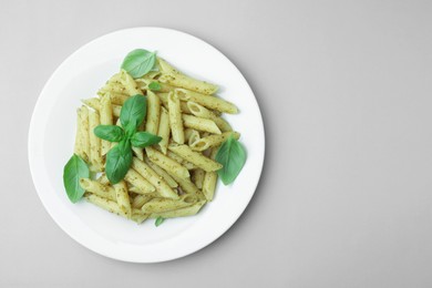 Delicious pasta with pesto sauce and basil on light grey background, top view. Space for text