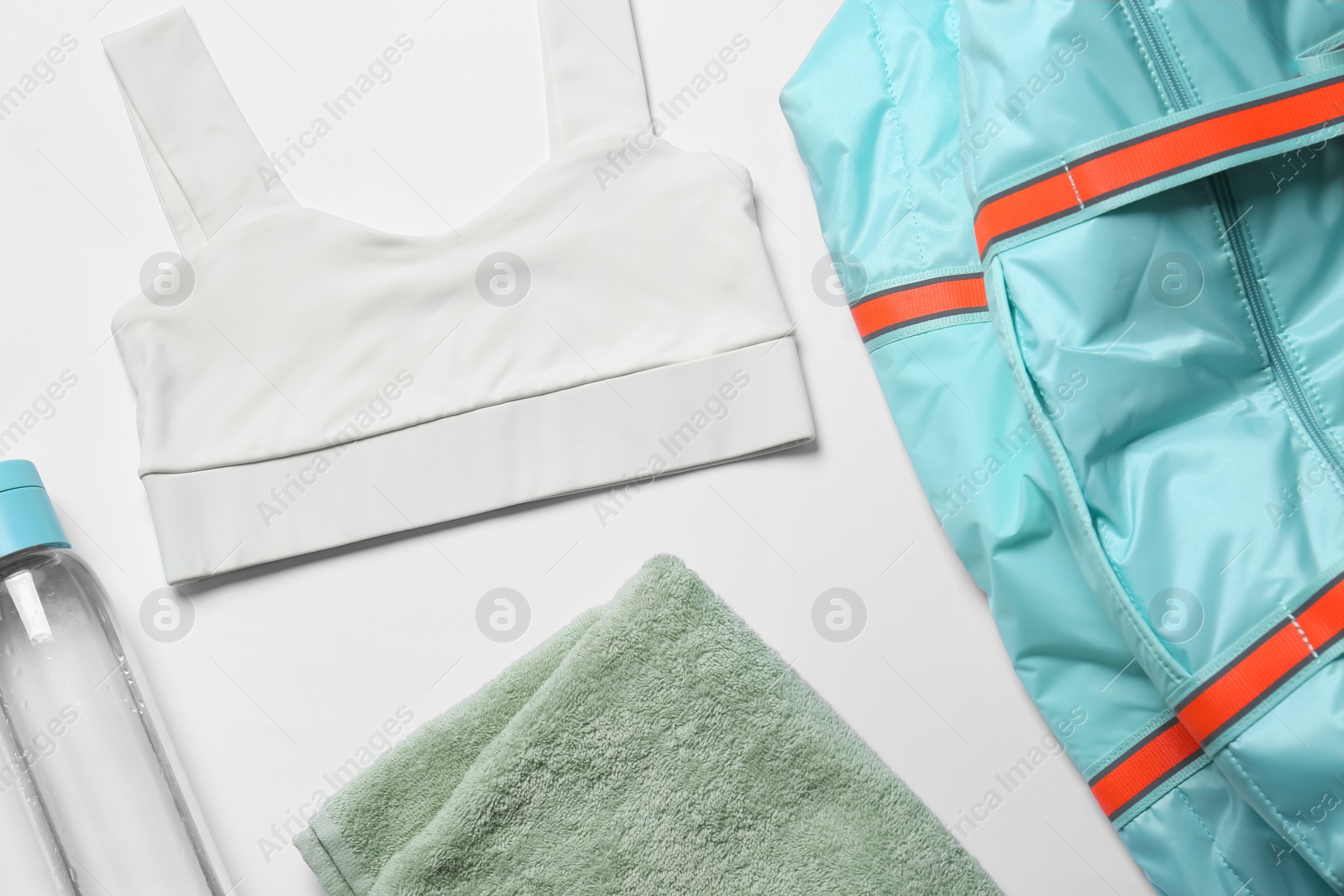 Photo of Gym bag, yoga sportswear, towel and bottle of water on white background, flat lay