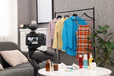 Beauty blogger's workplace. Cosmetic products, camera and clothes indoors