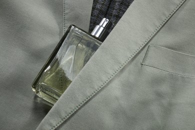 Photo of Luxury men's perfume in bottle on grey jacket, top view. Space for text