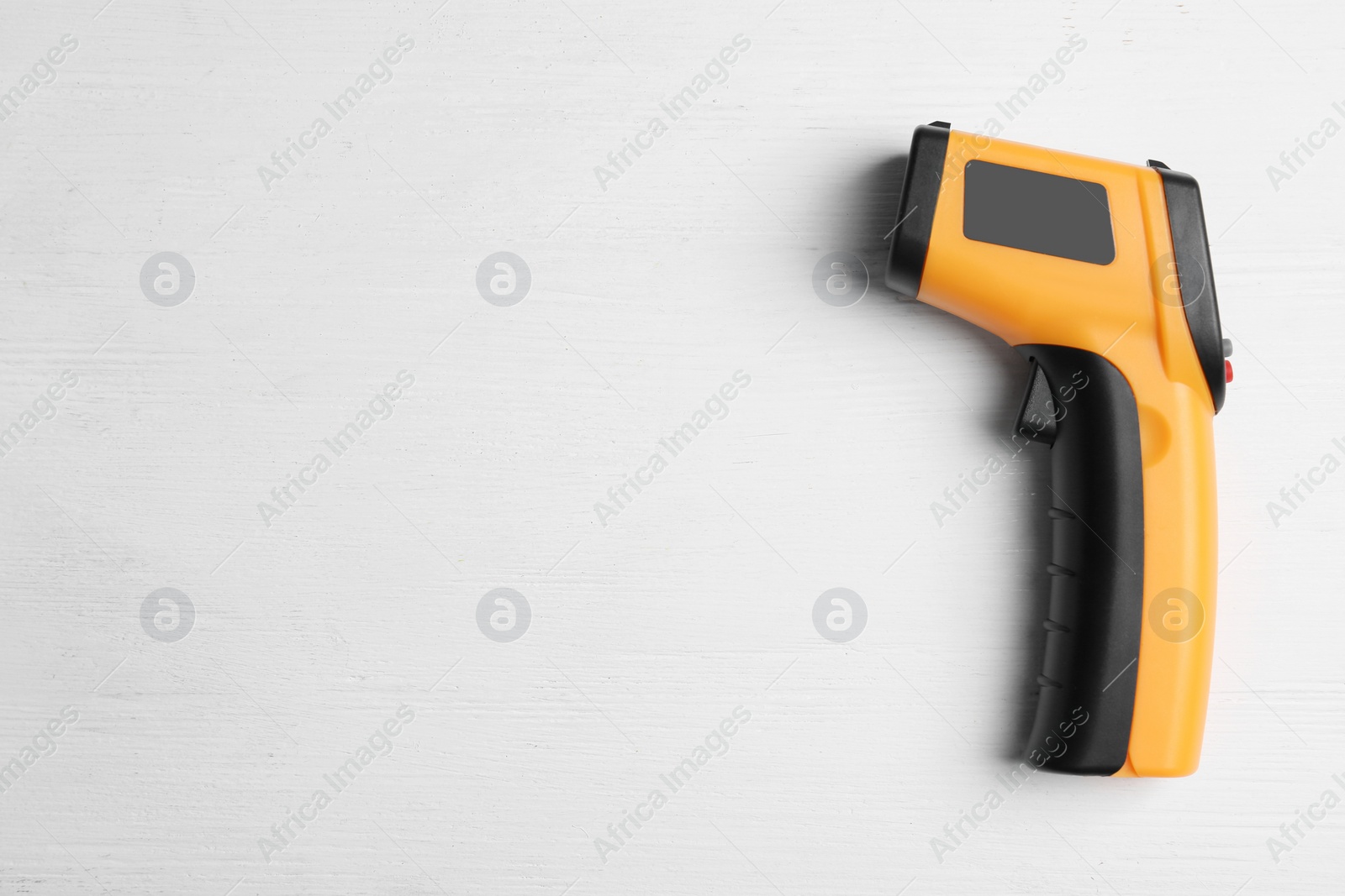 Photo of Modern non-contact infrared thermometer on white wooden background, top view. Space for text