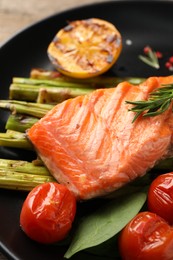 Tasty grilled salmon with tomatoes, asparagus and rosemary on plate, closeup