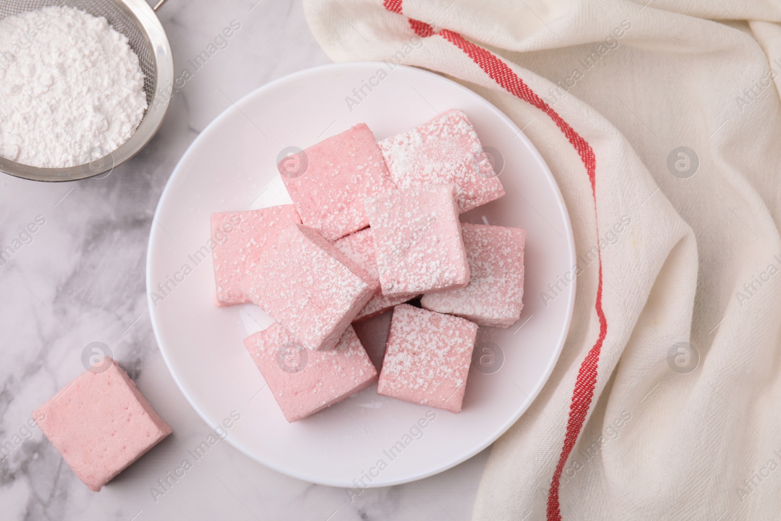 Photo of Plate of delicious sweet marshmallows with powdered sugar on white marble table, flat lay