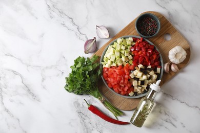 Photo of Cooking delicious ratatouille. Fresh ripe vegetables and plate on white marble table, flat lay. Space for text