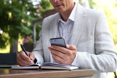 Photo of Businessman with smartphone working in outdoor cafe, closeup