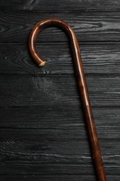 Photo of Elegant walking cane on black wooden table, top view