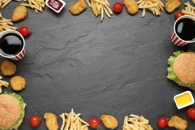Photo of Frame of delicious fast food menu on black table, flat lay. Space for text