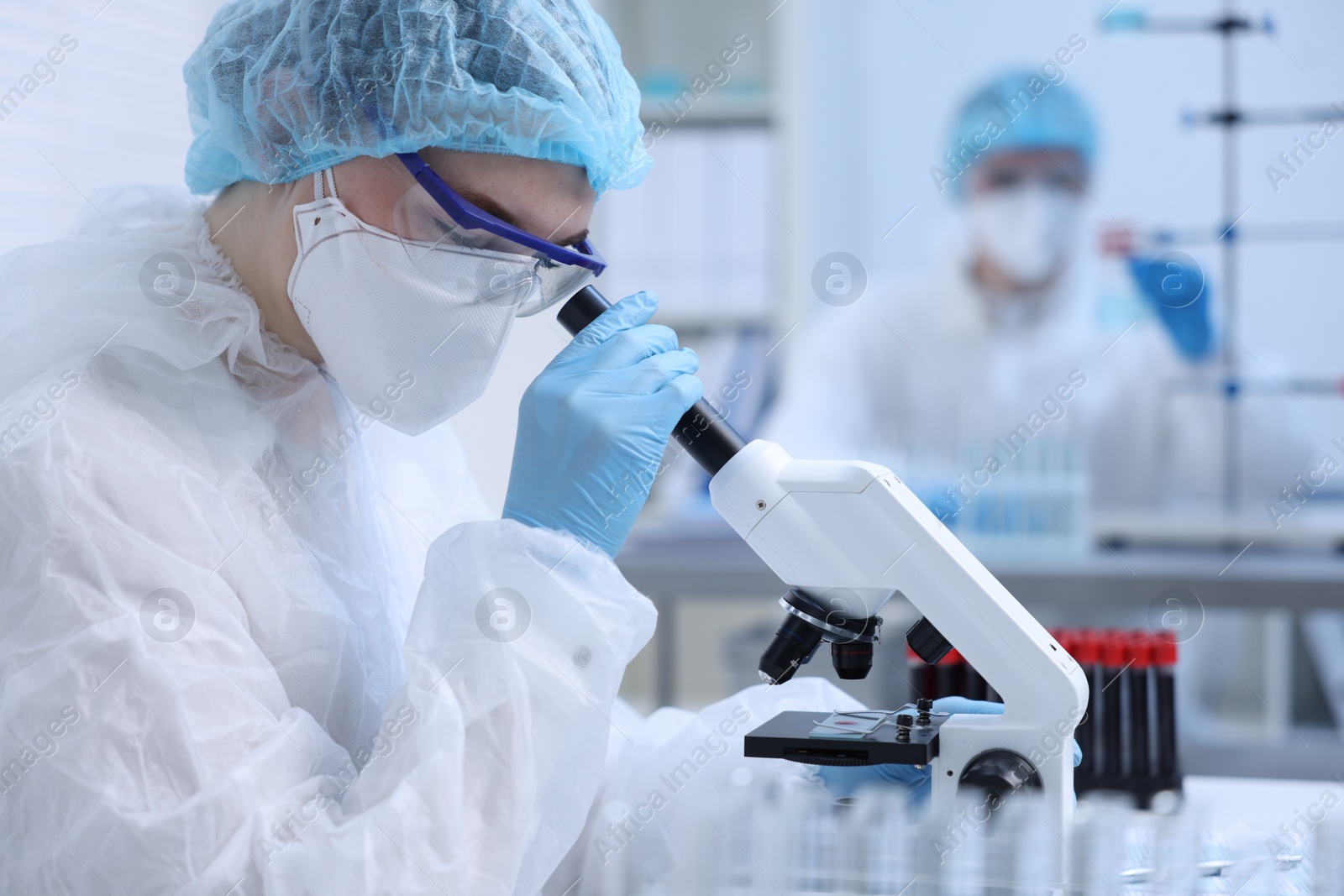 Photo of Scientist working with samples and microscope in laboratory