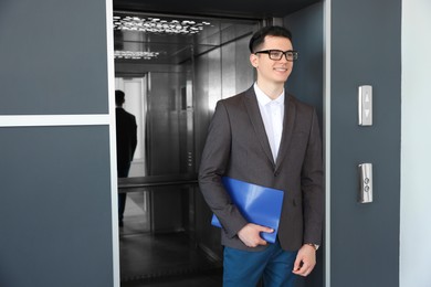 Young businessman walking out of modern elevator