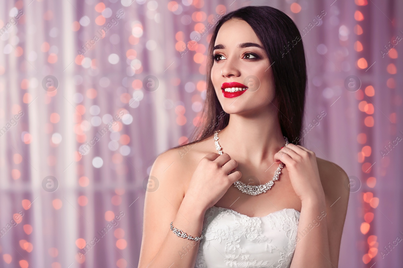 Photo of Beautiful woman with stylish jewelry against blurred lights, space for text