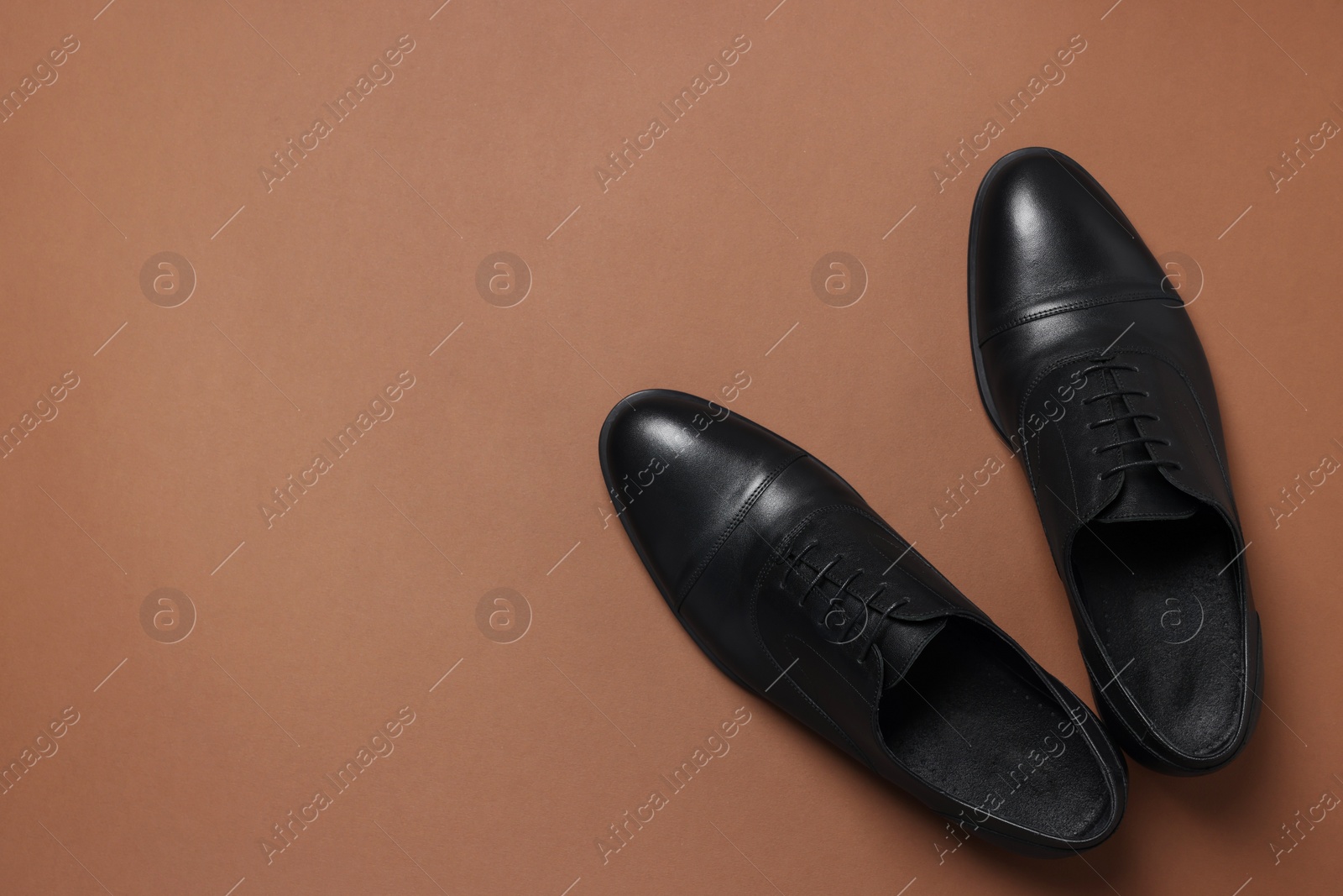 Photo of Pair of leather men shoes on brown background, top view. Space for text